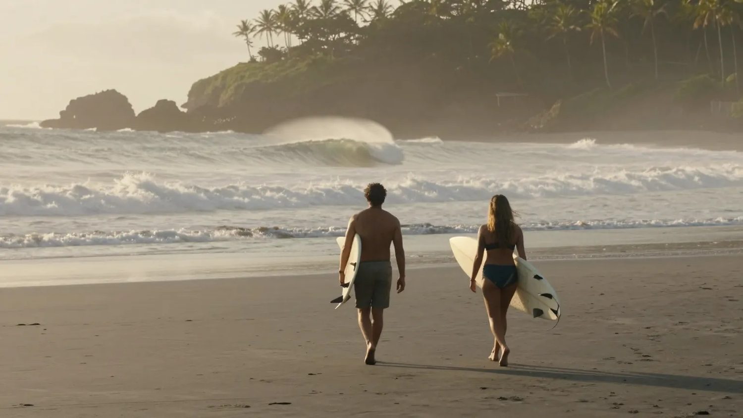 Two surfers walking the tide line with their boards